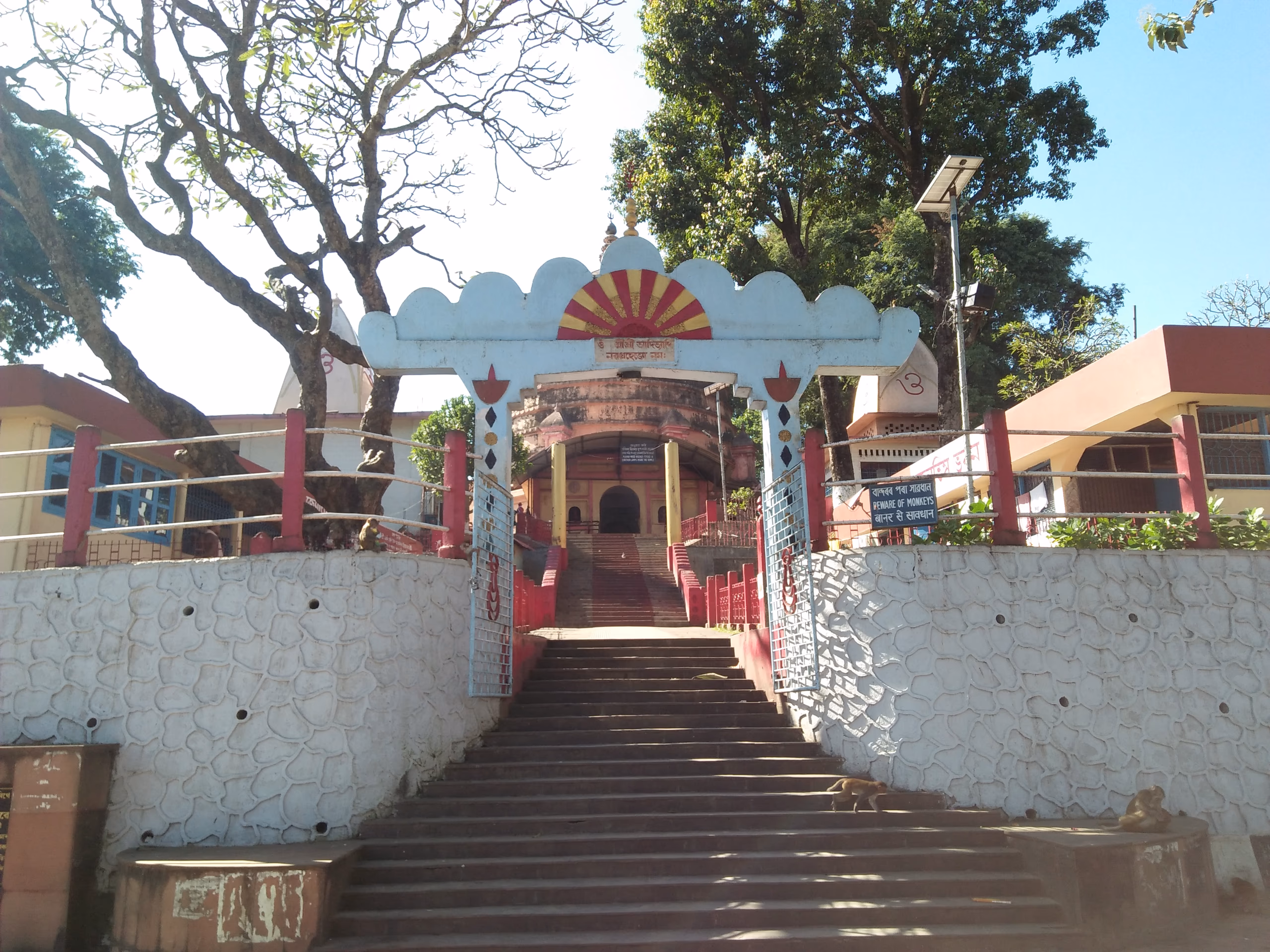 An ornamented archway painted with a red-and-orange sunburst over the flight of steps climbing to the Navagraha temple