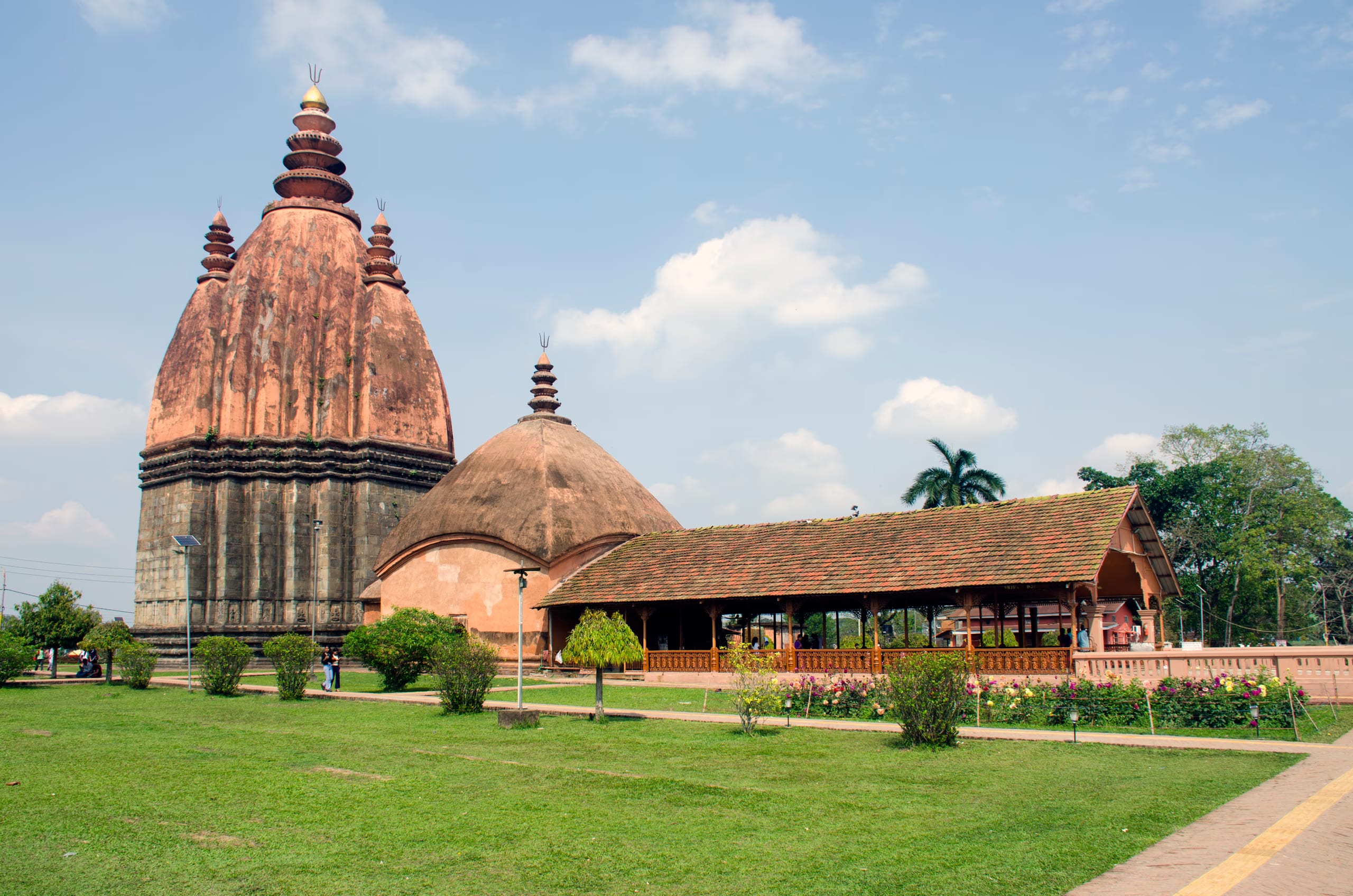 The tall curvilinear brick spire of the Sivadol rising above its mandapa hall at Sivasagar