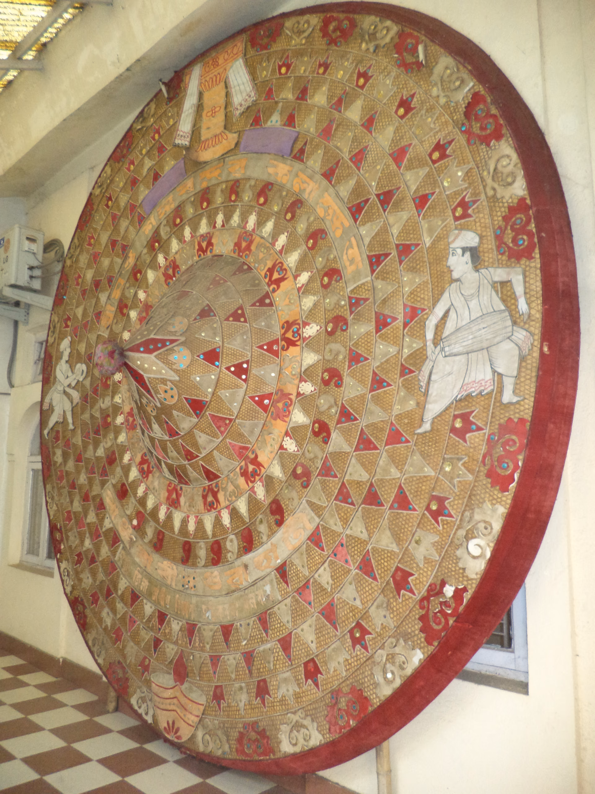 A very large phulam japi faced in red and gold cloth, worked all over with triangular appliqué, mirrors and figural motifs