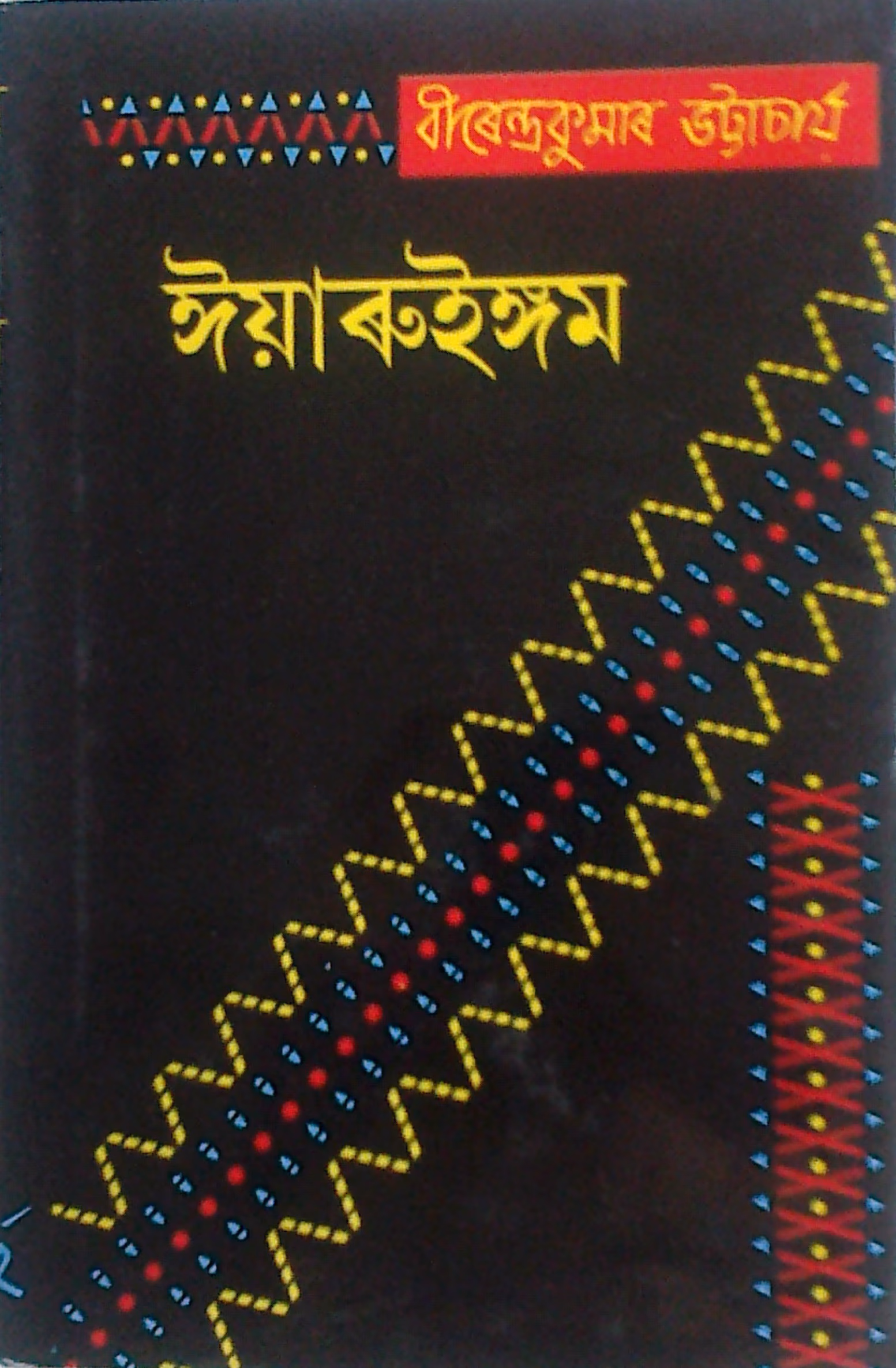 Black book cover printed with the Assamese title Iyaruingam and the author's name, with a woven tribal-textile motif running diagonally