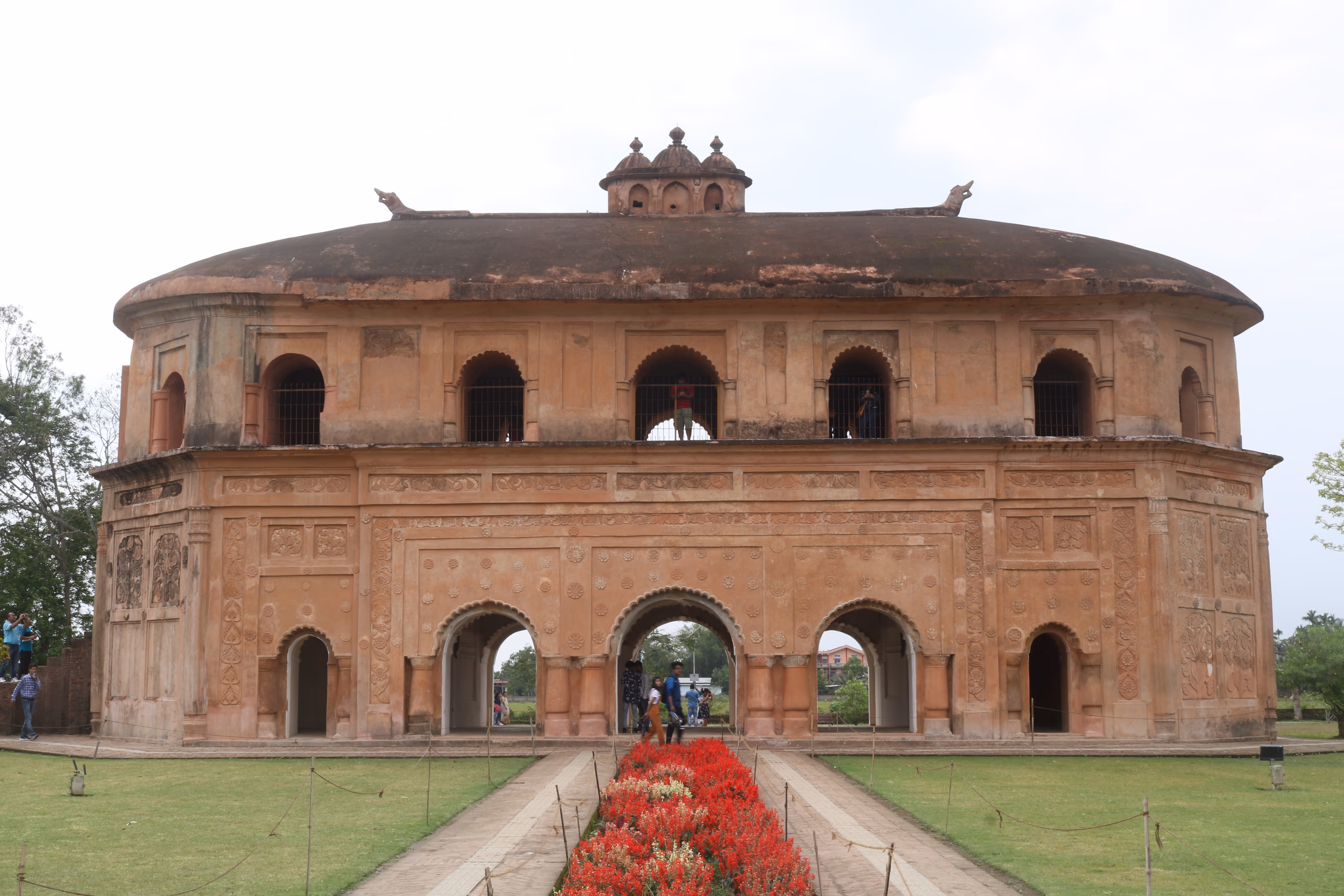 The Rang Ghar, the two-storey oval Ahom royal pavilion with a boat-shaped roof, seen frontally across its garden path